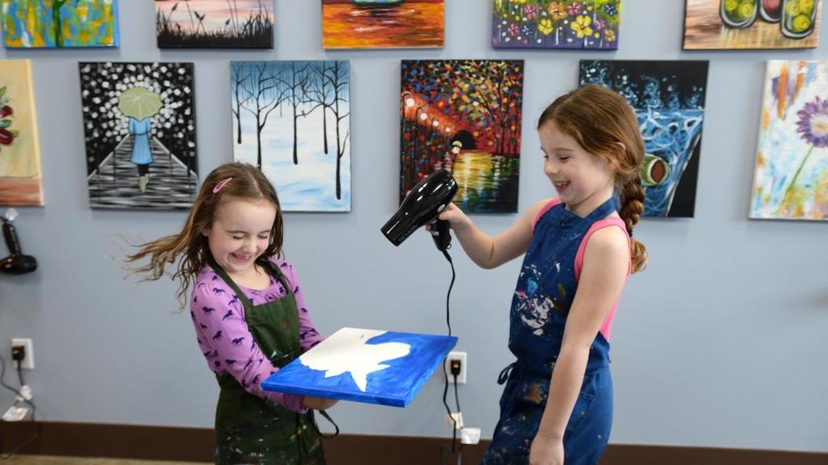 Raegan Wheeler, 8, gets a little wind blown in her face while helping friend Kaitlyn Andrews, 8, dry a painting of a unicorn at the new location of Uptown Art studio at 800 Harris Ave., No. 101 in the Fairhaven District of Bellingham, Thursday, April 13, 2017. The paint and sip art studio will have an open house at 3 p.m. on Thursday, April 27.