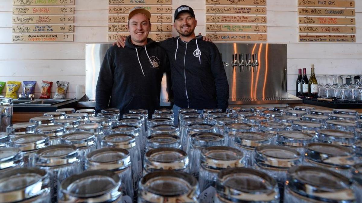 Owners Adam Stacey, left and Jesse Nelson, stand behind the bar in the second location of Overflow Taps in Barkley Village in Bellingham Tuesday, Aug. 15, 2017. The tap house donates 25 cents to a clean water charity for every pint sold.