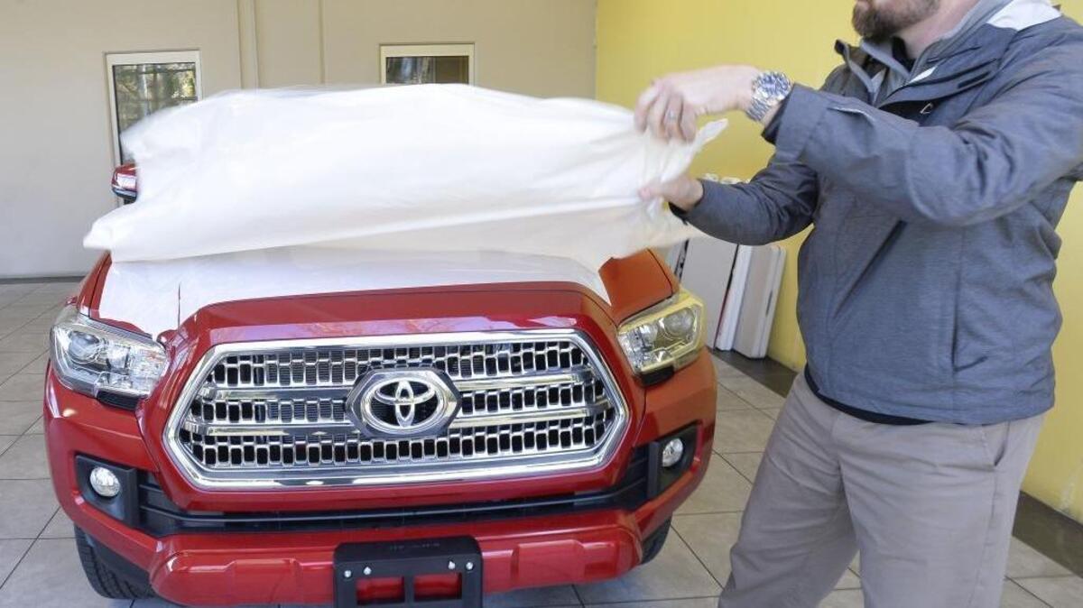 Salesman Richard Brunell at Wilson Moters takes the protective plastic off a new 2016 Toyota Tacoma in November 2015. Wilson Motors has sold its Toyota/Mercedes-Benz and its Nissan dealerships to separate owners.
