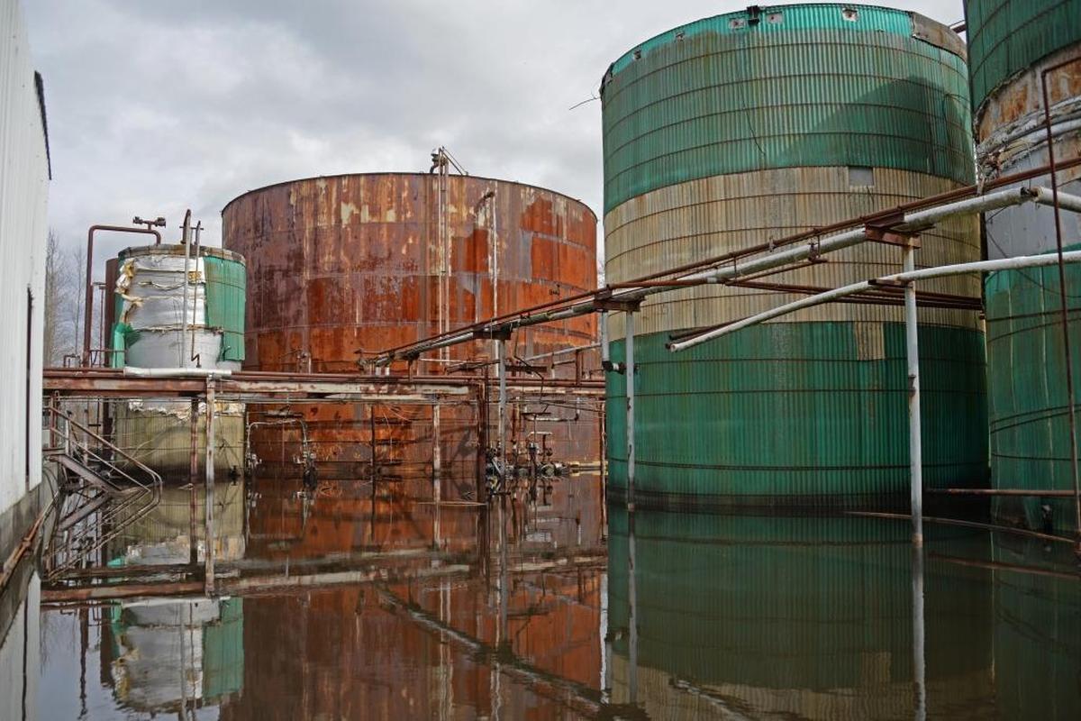 Large rusting tanks are reflected in the water at TreOil Industries on Aldergrove Road north of Ferndale on Friday, March 31, 2017. The EPA is coordinating the emergency cleanup of the abandoned biofuels processing plant and says it contains around 30,000 gallons of tall oil, as well as other chemicals, that are in danger of leaking into the environment.