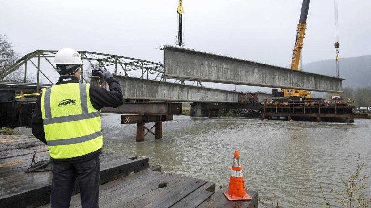 Senior Bridge Engineer Jiri Pertold of David Evans and Associates who designed the new Potter Road bridge takes a photo on his phone as a nearly 120-foot long girder is installed on Oct. 29, 2014 near Van Zandt. Crews will limit traffic from Feb. 23 to 26, 2016, to install pedestrian railing.