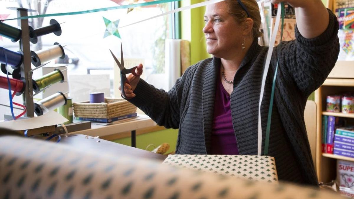 Volunteer Diane Sanders-Rehberger wraps gifts at Fairhaven Toy Garden for donations to nonprofit organization Carry The Future on Dec. 24, 2015, in Bellingham for last-minute holiday shoppers. Fewer Canadian shoppers were at Whatcom County stores like Fairhaven Toy Garden this holiday season, but some stores saw an increase in shoppers from other areas to the south, such as Skagit and Island counties.