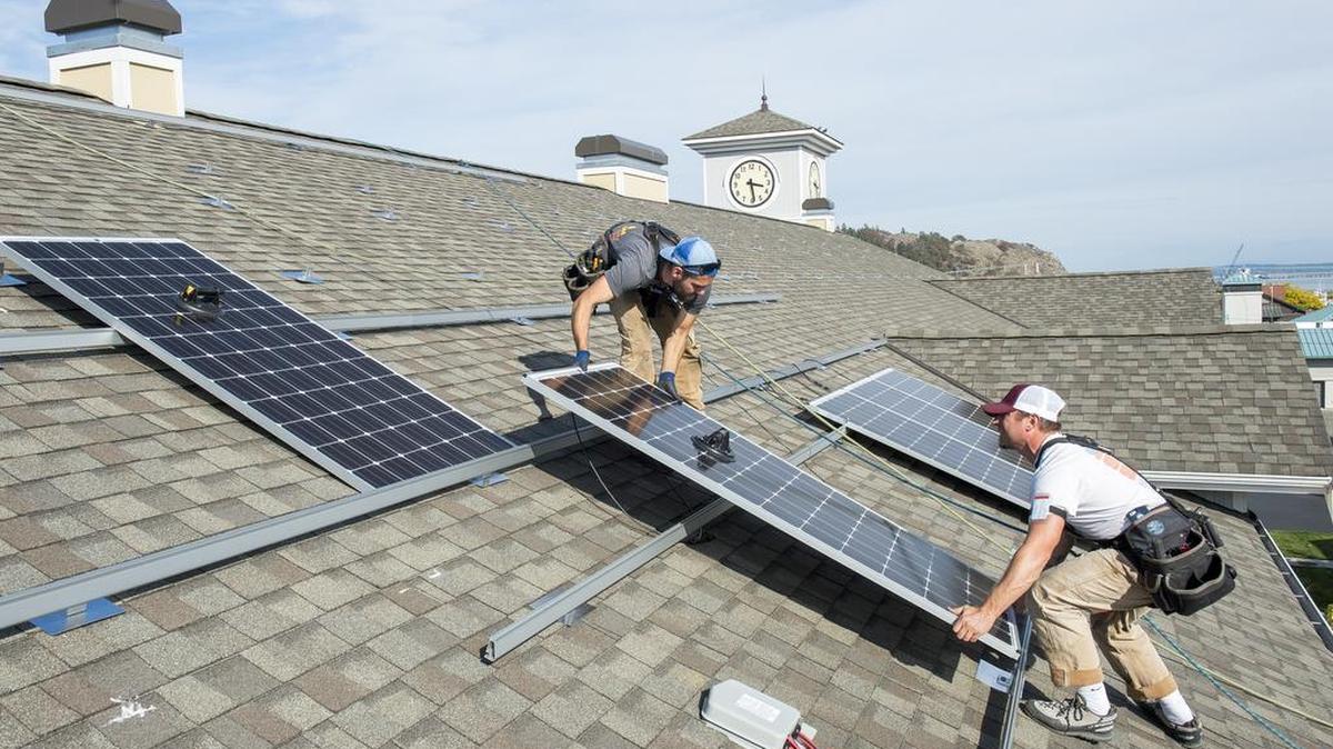 Echotech Energy Systems employees Andy Davis, left, and Yonk Reinemer install solar panels on the roof of Chandler’s Square Retirement Community on Thursday, Sept. 29, in Anacortes. When the project is finished there will be 150 solar panels on the roof and 495 total in the complex.