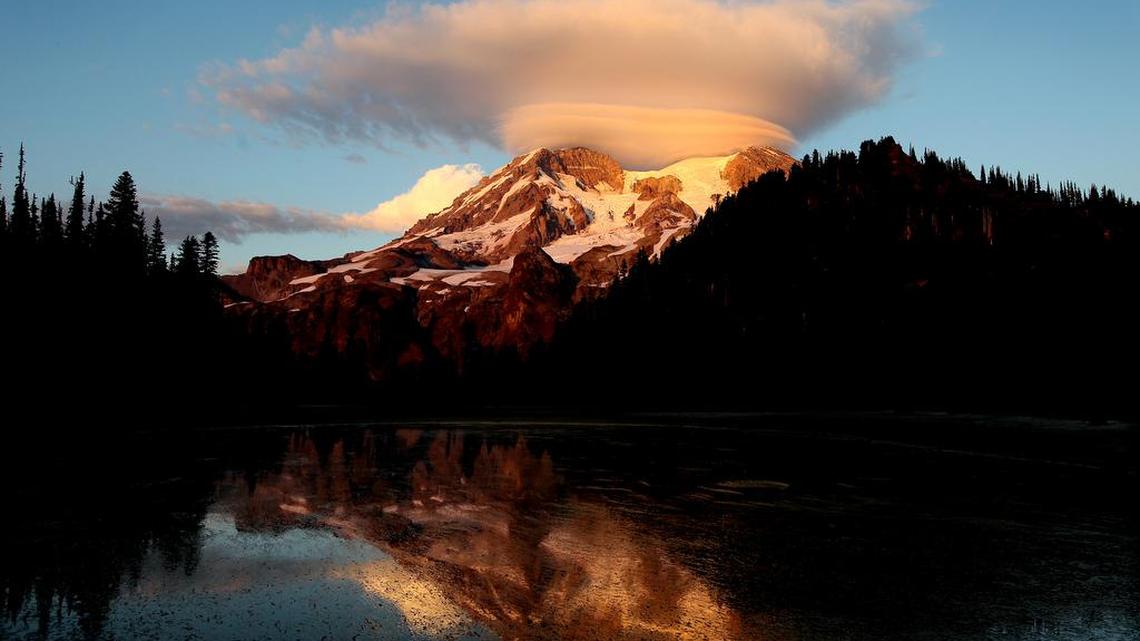 In this September 2012 photo, a cloud hovers over Mount Rainier at sunset in a view from Klapatche Park Camp at Mount Rainier National Park in Washington.