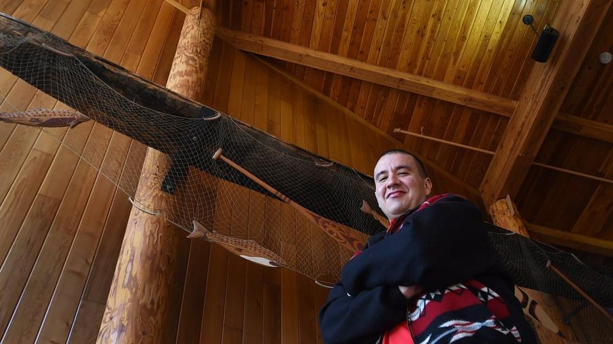 Nisqually tribal member Willie Frank Jr. III stands below the elevated canoe used by his father, Billy Frank Jr. The canoe is on display at the Wa He Lut Indian School in Nisqually.