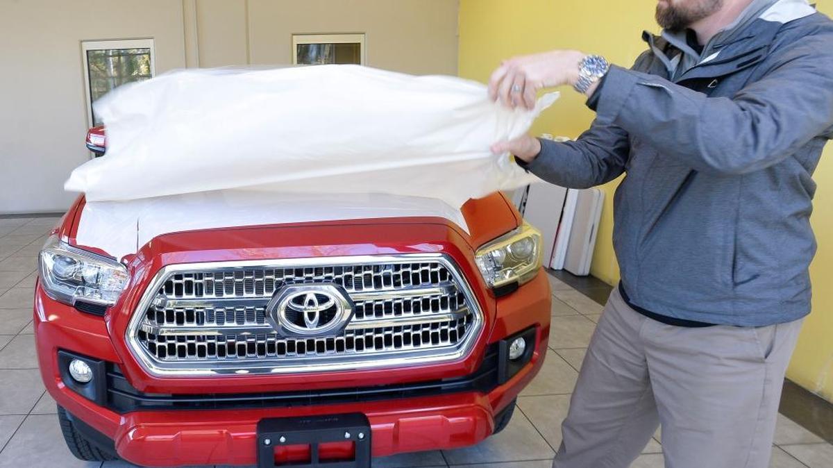 Salesman Richard Brunell takes the protective plastic off a new 2016 Toyota Tacoma on Monday, Nov. 9, at Wilson Motors in Bellingham. New car sales in Whatcom County were up in the second quarter of 2015.
