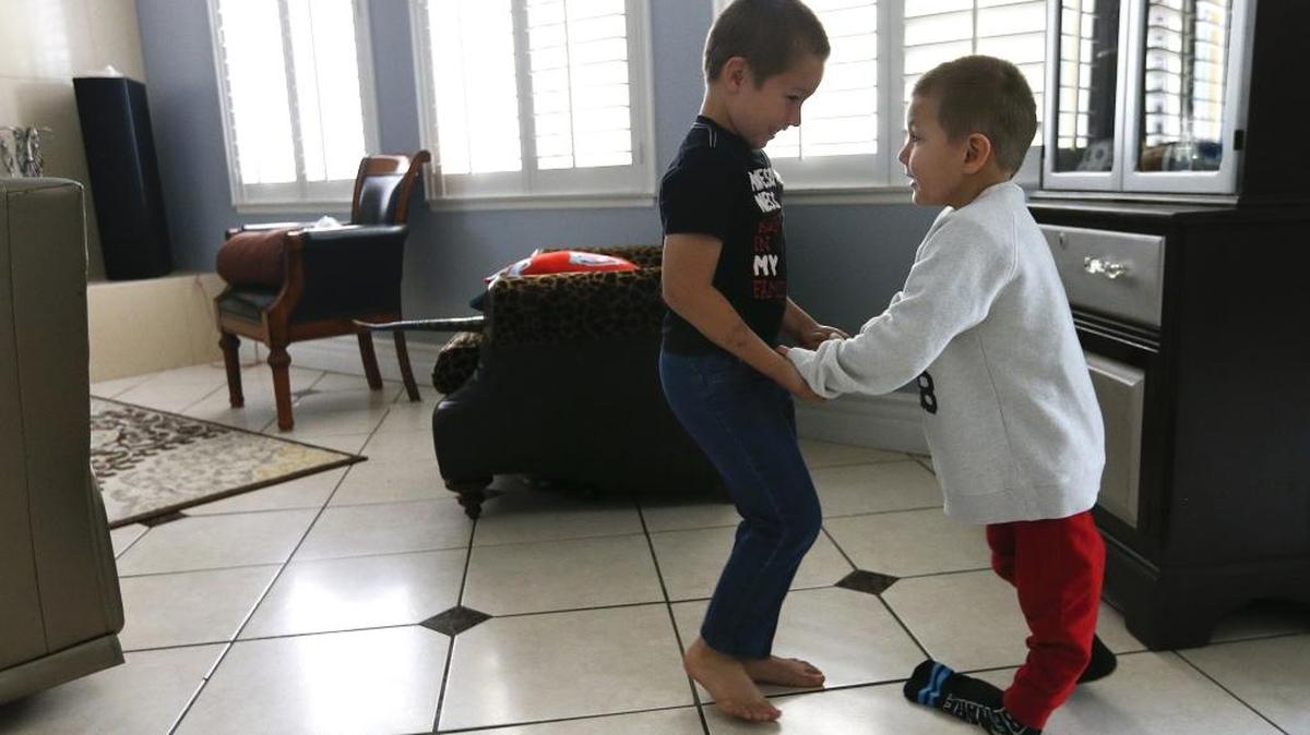 Nikolas Olivera, left, helps his brother Lucian while walking together on March 28, 2016, inside their home in Moorpark, Calif. Lucian suffers from a condition called acute flaccid myelitis, which causes polio-like symptoms. His left leg is paralyzed and his right leg is partially paralyzed. (Mel Melcon/Los Angeles Times/TNS)
