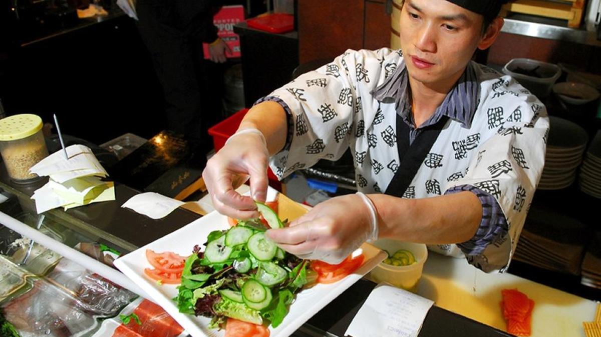 
Andy Mei, an owner of A.W. Asian Bistro in Fairhaven, places slices of cucumber onto a bed of mixed greens as he prepares a Wasabi Salmon Green salad at the restaurant on May 14, 2008.
