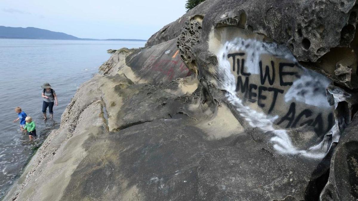 Lauren McDermott and her sons Sawyer McDermott, 3, and Kaden McDermott, 5, walk in water by the rocks sprayed with graffiti at Clayton Beach in Larrabee State Park south of Bellingham on Tuesday, May 17, 2016. “It’s sad to see this type of disrespect,” McDermott said.