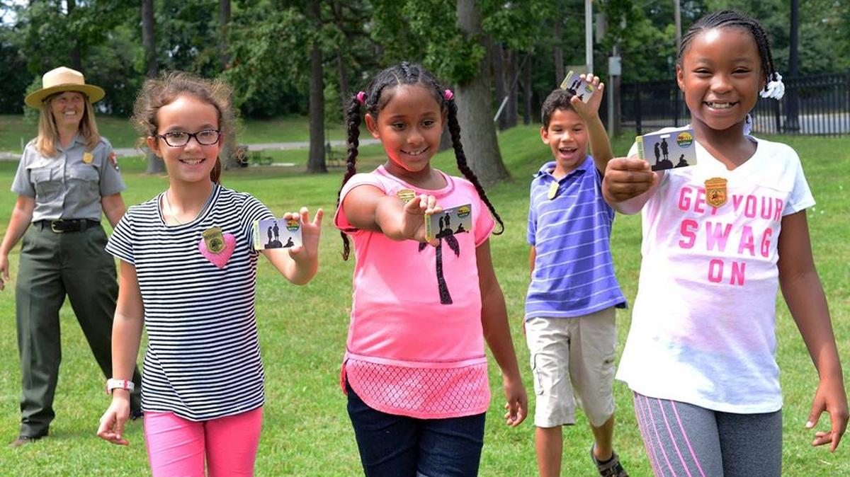 
Fourth-graders on the grounds of Samuel W. Tucker Elementary School in Alexandria, Va., hold passes on Aug. 24 that give them and their families free admission for one year to all national parks. The National Park Service has announced an initiative called “Every Kid in a Park,” which makes the annual $80 passes free for fourth-graders and their families. 
