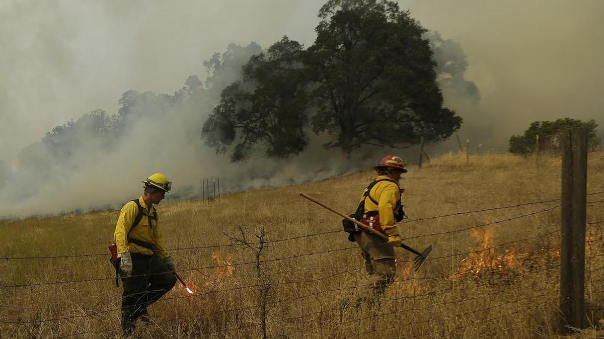 A fire crew works a back fire along Morgan Valley Road near Lower Lake, Calif., Wednesday, Aug. 12, 2015. Erratic winds fanned a wildfire burning through rugged hills in Northern California on Wednesday, pushing the flames across two counties and smoke as far north as Washington state.
