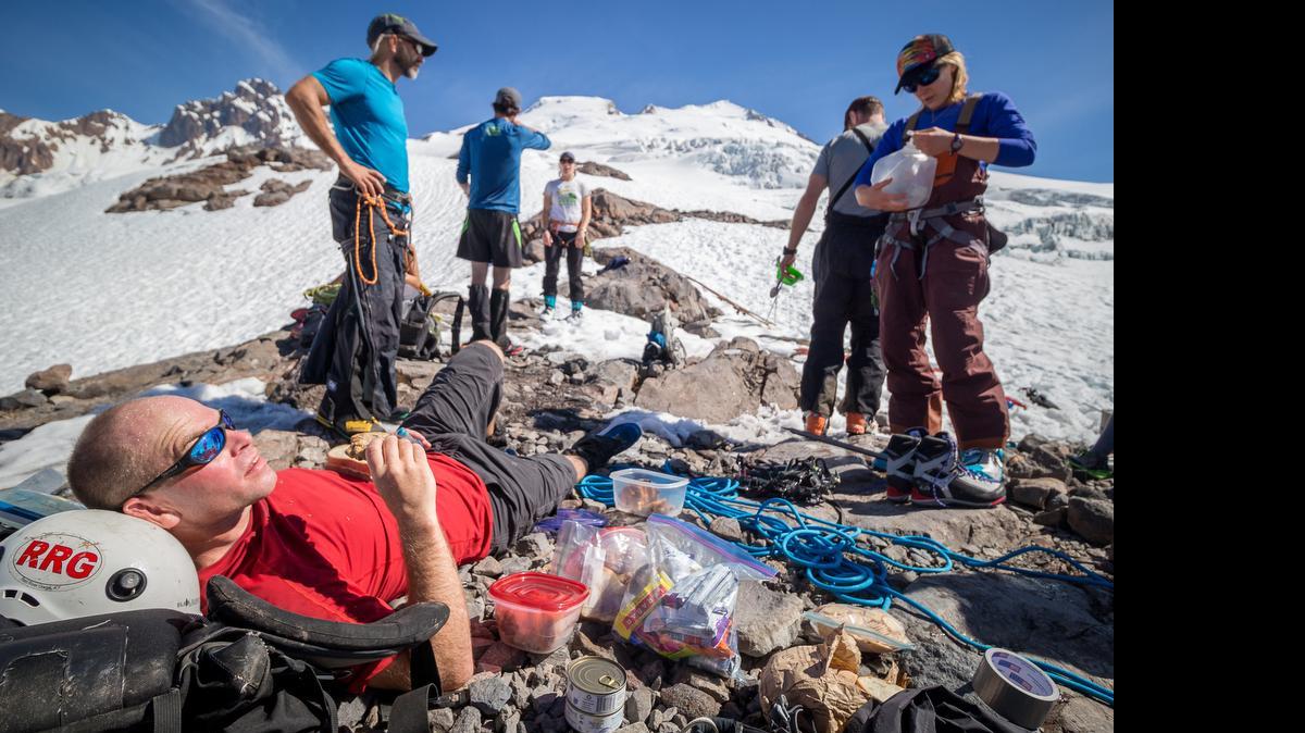 
Bellingham ultra-runner Daniel Probst, in red, relaxes while eating two cookies and a sandwich Saturday, June 6, 2015, while at just over 6,000 feet at the base of Easton Glacier as the support team helps Probst and three other runners refuel and transition to crampons and ropes. Three runners successfuly completed a 108-mile run, hike and climb from Bellingham Bay to Mount Baker and back.
