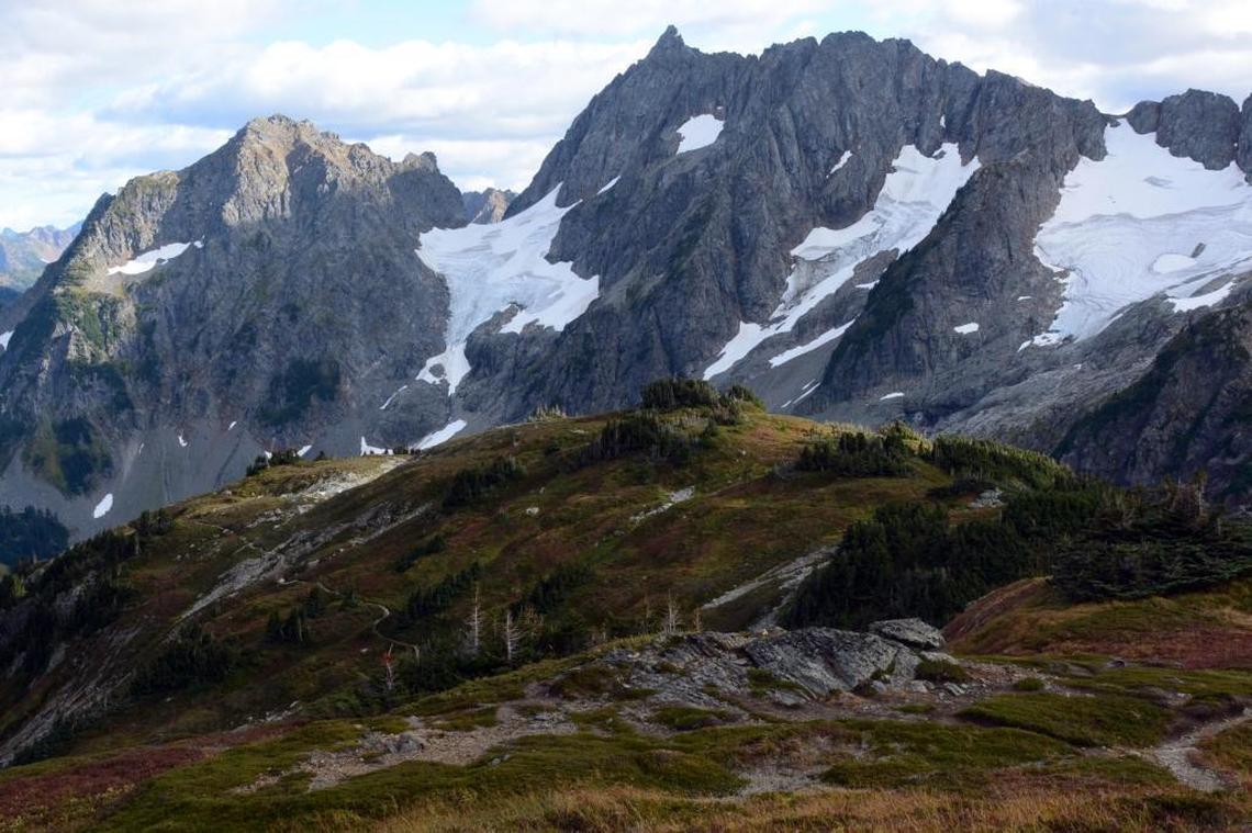 A trail winds up an arm of Sahale Mountain, off the Cascade Pass trail, to views of Pelton Peak (left), Yawning Glacier, and Magic Mountain, at North Cascades National Park. The park announced it’s trying out a new reservation system this summer for some of its most popular backcountry campsites.