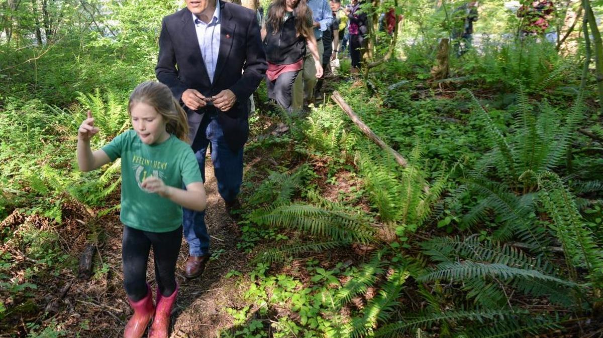 Northern Heights Elementary student Archer Burns, 8, leads Washington Gov. Jay Inslee on a walk in the woods near the school in Bellingham, Monday, April 25, 2016. Inslee was at the school to announce grants for a “No Child Left Inside” program to promote outdoor education. Wild Whatcom received $20,000 to teach outdoor education for second graders in the Bellingham School District during the next school year.