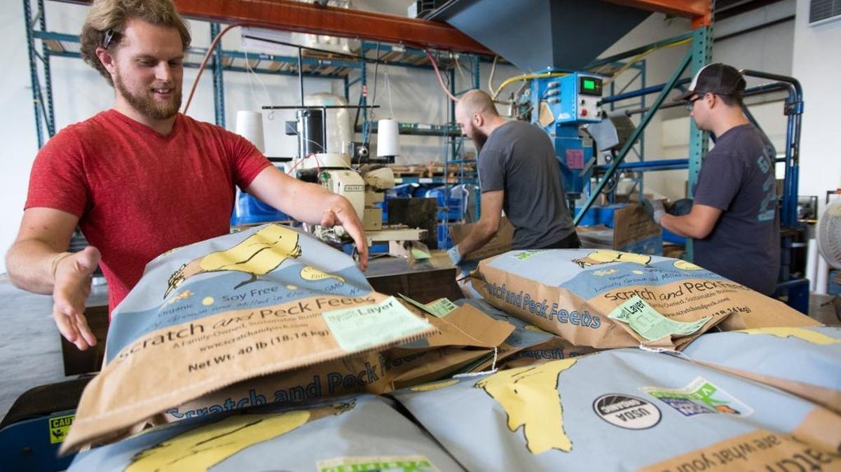 
Scratch and Peck Feed employees, from left to right, Ben Black, Taber Wilmot and Derek Bradley package feed on Wednesday, Sept. 16, in Bellingham. Scratch and Peck Feeds is one of 20 small companies nationwide recently awarded a $100,000 grant from Chase bank.
