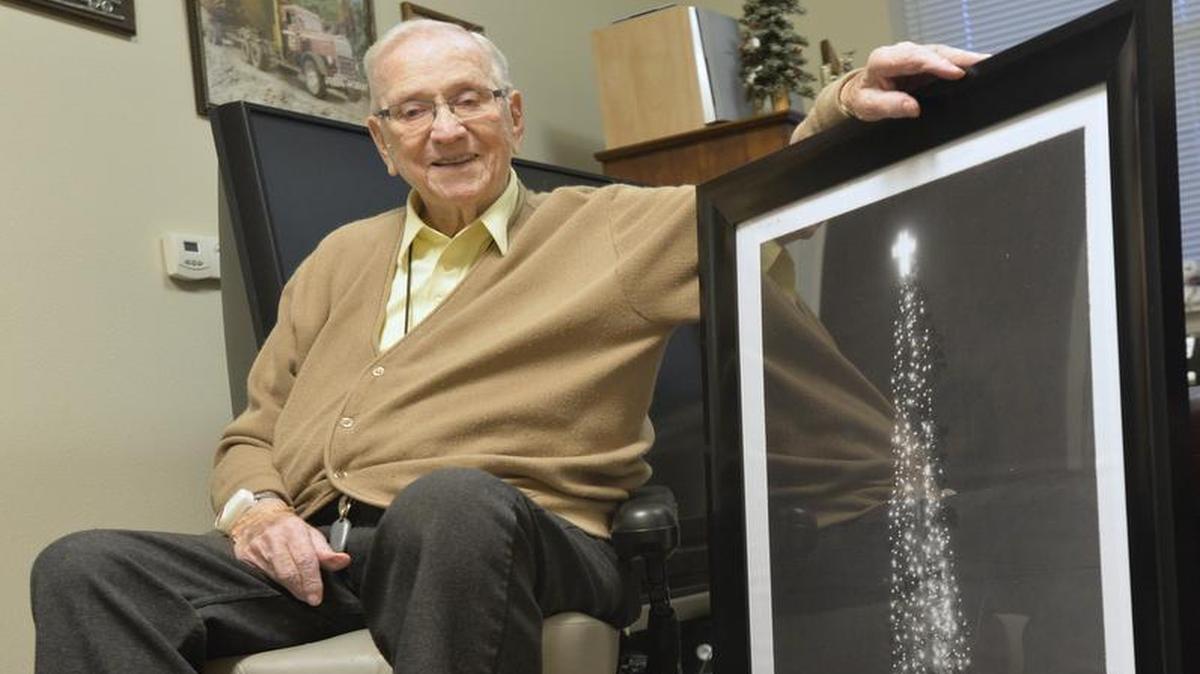 Shown in 2014 at his Bellingham apartment, Abner Ludtke displayed a photo of the nearly 153-foot Christmas tree he hauled to downtown Bellingham in 1949. Ludtke died June 6, 2016. He was 99.