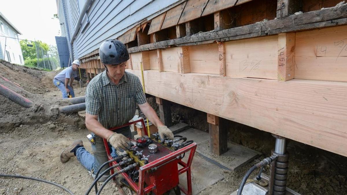 Bill Erickson, left, of the Franklin Corporation watches as Rick VanderVeen of VanderVeen House Moving uses an air compressor connected to jacks to raise one side of the Bellingham Theatre Guild building in Bellingham on Monday, July 18, 2016. The installation of a new foundation and an elevator are part of a $1 million capital improvement campaign for the 1902 building.