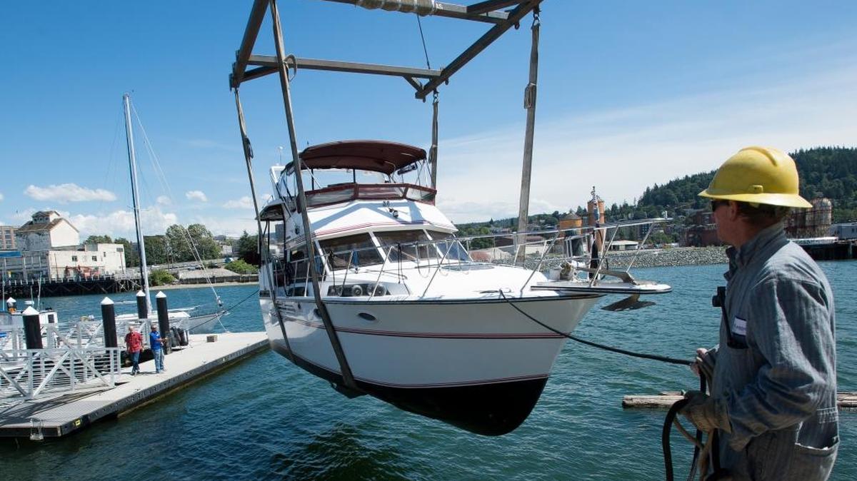Landings at Colony Wharf employee Blane Jackson, right, helps steady a boat as its lowered into the water by a crane on Friday, June 17, in Bellingham, Wash.