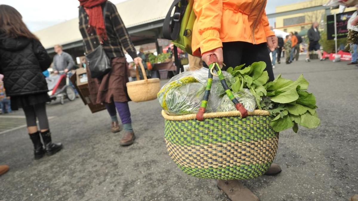 A market-goer holds a basket full of greens as the Bellingham Farmers Market on the April opening day in 2013. The winter version of the market, which happens one Saturday a month, returns Jan. 16 in 2016.
