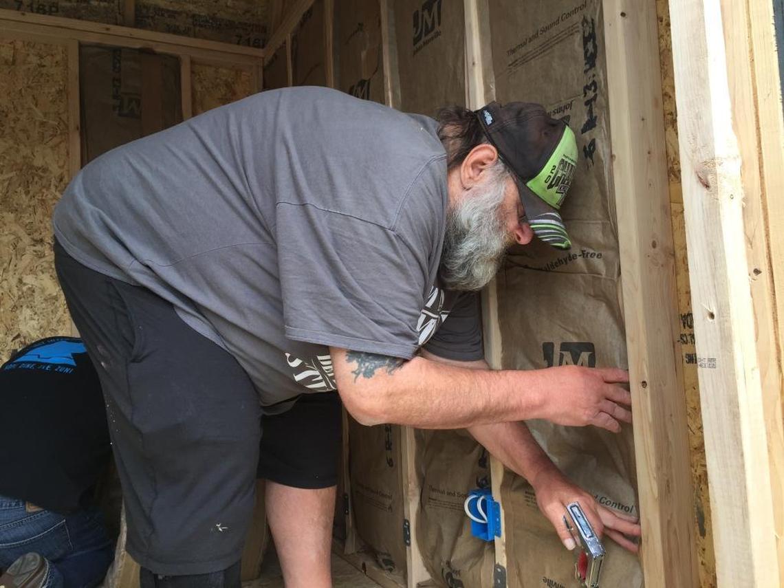 Jim Peterson with HomesNOW! staples siding into the organization’s first tiny home. The home aims to have someone living inside it by Sunday night.