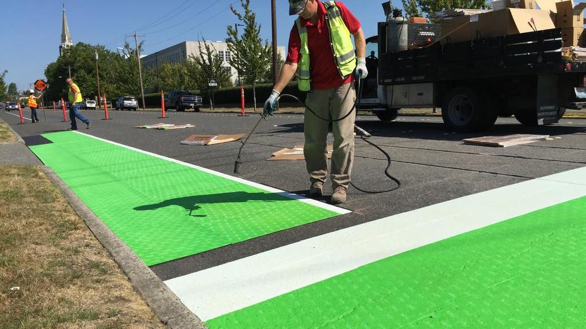 Darrin Kamps, owner of Kamps Painting Co. of Lynden, uses a propane torch to apply bicycle markings in the summer of 2015.