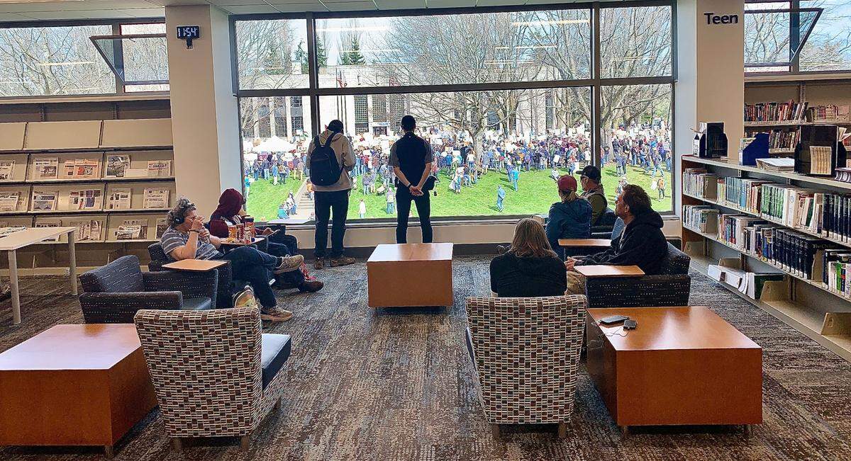 Patrons on the second floor of the Bellingham Public Library watch protesters gather at City Hall on Saturday.
