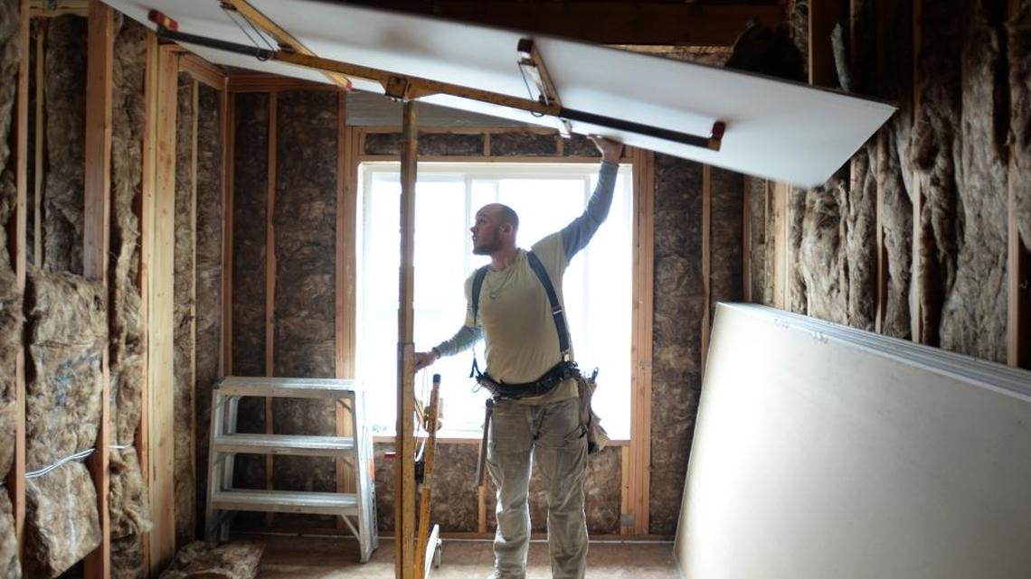 Cascade Drywall's Jordan Snow lifts up a piece of drywall while working in the Garden Street Flats apartment building under construction in Bellingham on Tuesday, April 4, 2017. The 14-unit building is expected to be finished in July.
