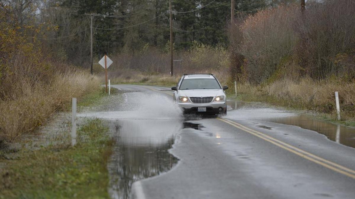 Cars drive through receding flood water on Marine Drive west of Ferndale Road Monday, Nov. 16, 2015. Another round of wind and rain are expected through Tuesday. 