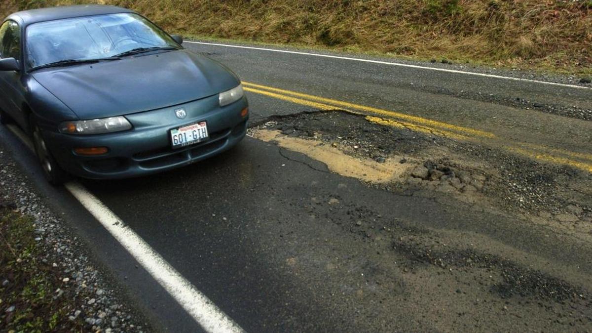 A car maneuvers around a large pothole in Whatcom County in 2005. This year’s potholes are the worst they’ve been in years after an especially cold winter.