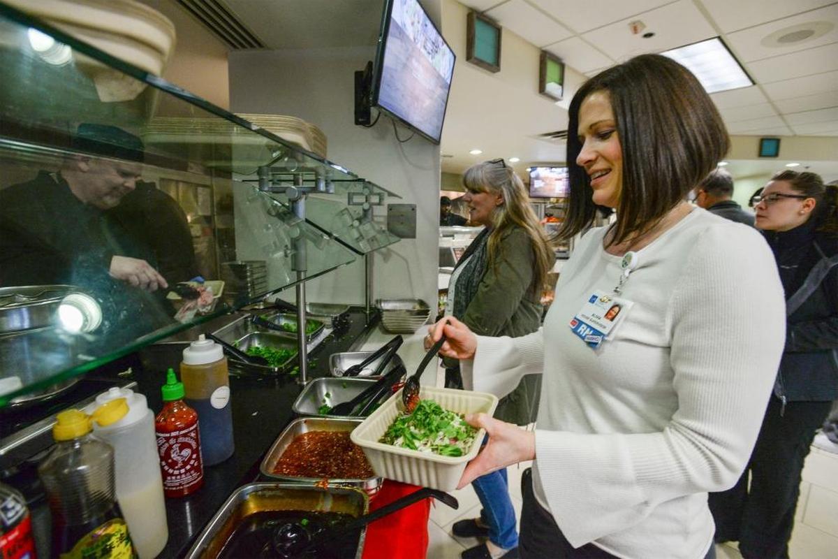 Registered nurse Alivia Vega, a house supervisor at St. Joseph hospital, adds sambal oelek to her Vietnamese pho during lunch on Jan. 19, 2018, in the cafeteria. Made by employee Khanh Trinh, the fragrant noodle soup is a favorite on Fridays, when it is served.