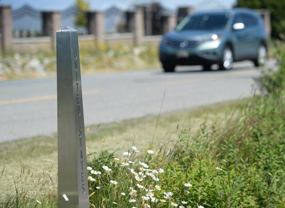 A car drives on 0 Avenue in Canada, behind an obelisk in the ditch that marks the U.S.-Canada border north of Lynden, Washington on Thursday, June 22, 2017.