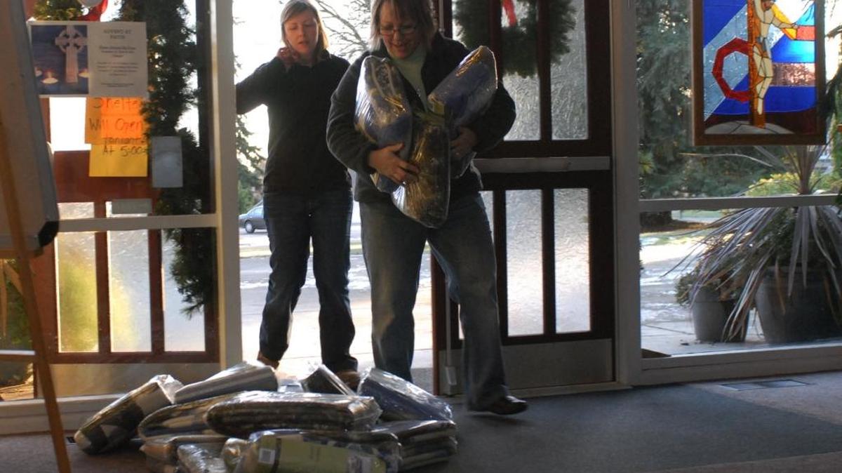 In this 2008 file photo, Shari Matthews, front, and Rebekah Swanson bring in donated blankets while preparing to open the Interfaith Coalition men’s cold weather shelter. The men’s shelter and a separate one for women and children will open the nights of Nov. 24 and 25, 2015, because of expected freezing weather.