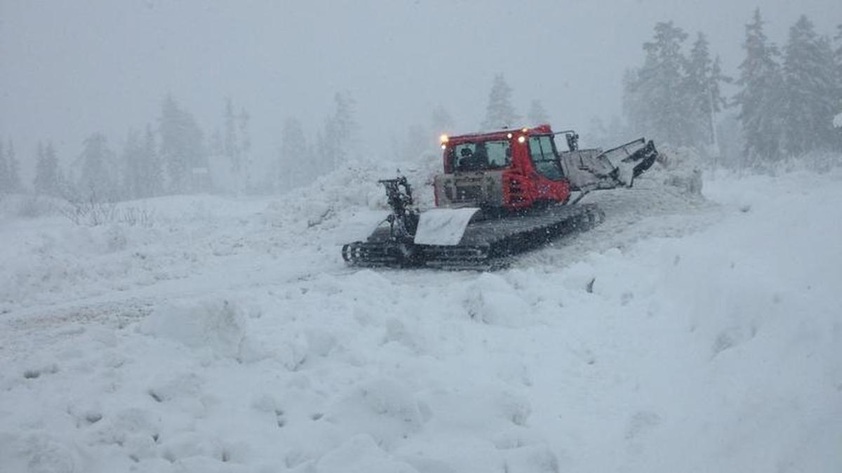 A tracked vehicle moves through deep snow as heavy snow falls near where searchers are looking for two snowboarders who have been missing since Sunday. They left their car at the Heather Meadows parking lot.