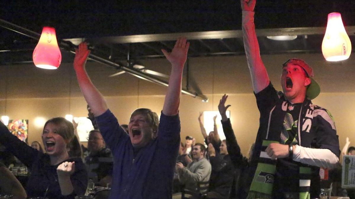 Nicole Murray, left, Ethan Miller, center, and Matthew Granito celebrate at New York Pizza and Bar in Bellingham as the Seattle Seahawks defeat the Denver Broncos in the 2014 Super Bowl. The Herald is collecting a list of businesses hosting Super Bowl 50 parties.