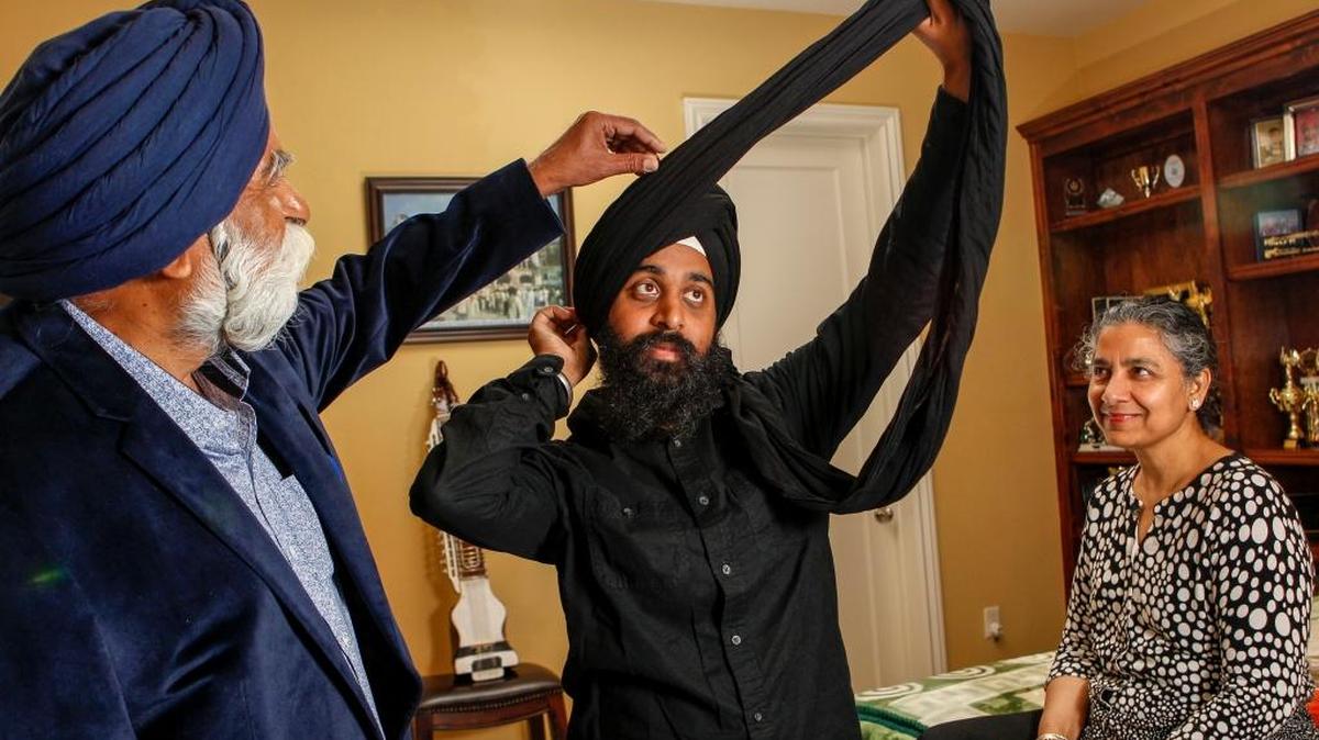Manbir Singh, left, and Taran Kaur watch their son Balmeet Singh, center, tie a turban called a dastar on April 14, 2017 in Bakersfield, California. Balmeet Singh was the victim of a hate crime just before presidential elections in Bakersfield.