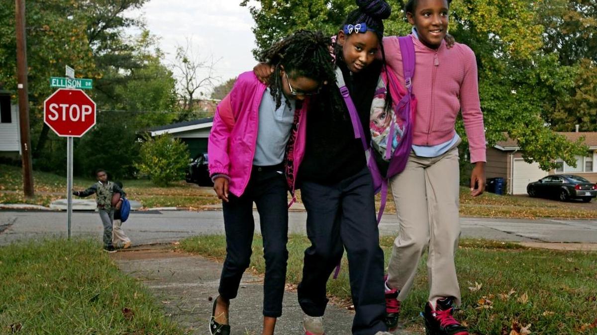 “It’s a best friend thing. We always be holding on to each other,” said Destiny Sommelier 10, right, who walks with friends Akeeylah Kelly, 8, and Saniya Bryant, 10, near their bus stop on Wednesday, Oct. 21, 2015, in Ferguson, Mo. The girls often walk past the home of deceased classmate Jamyla Bolden.