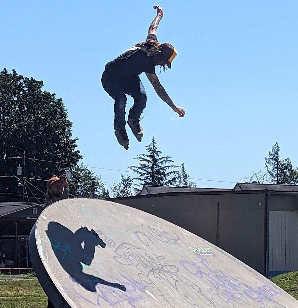 Inline skater performing jump while being photographed by fellow skater Cameron Talbott at the Lummi Skate Park on the Lummi Reservation on Friday, June 21, 2024.