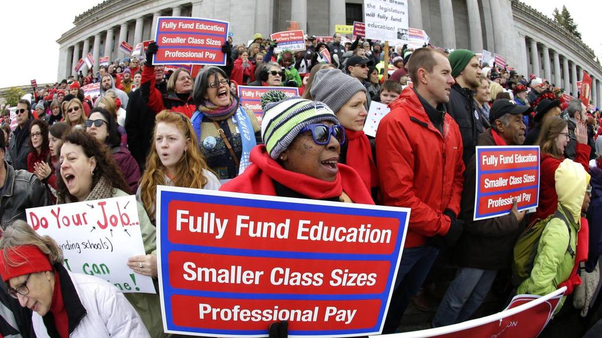 Oveta Hunter, center, an elementary school teacher from Seattle, cheers and holds a sign during a rally Jan. 16, 2017 in support of education funding at the Capitol in Olympia, Wash. The Washington State Supreme Court ruled Wednesday, Nov. 15, 2017, that while lawmakers have made progress, they are not on track to meet a court-imposed deadline to fully fund basic education, and will remain in contempt of court.