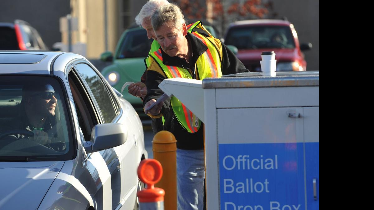 
Election worker Bob Cecile puts a ballot in the new drop-off box in the parking lot south of the Whatcom County Courthouse on Grand Avenue in Bellingham Tuesday morning, Nov. 2, 2010, while election worker Don Chadd gives voter Micah Gaston an " I voted" sticker.
