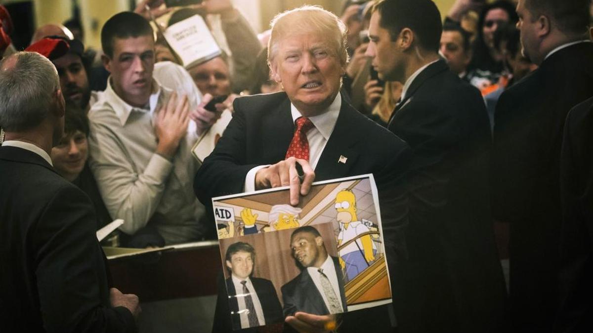 Republican presidential candidate Donald Trump holds depictions of himself on, “The Simpsons” and a photo with boxer Mike Tyson, given to him by an attendee during a campaign stop at the Radisson Hotel, Jan. 29, 2016, in Nashua, N.H.