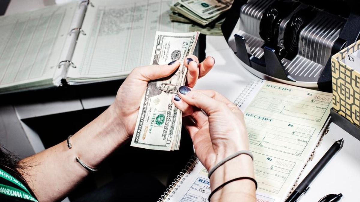 Paige Smith counts out money for payroll at Good Meds Dispensary in Lakewood Colo., Jan. 21, 2015. Several recently created companies are looking to solve one of the most vexing problems facing marijuana businesses; the endless flow of dirty, dangerous, hard-to-track cash.