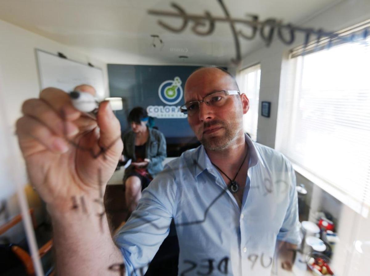 In this Wednesday, June 17, 2015 photo, Frank Conrad, head of pot-testing lab Colorado Green Lab, charts potency levels of marijuana while his co-worker, Cindy Blair, works behind, at the lab in Denver. In states that regulate marijuana, officials are just starting to draft rules governing safe levels of chemicals.