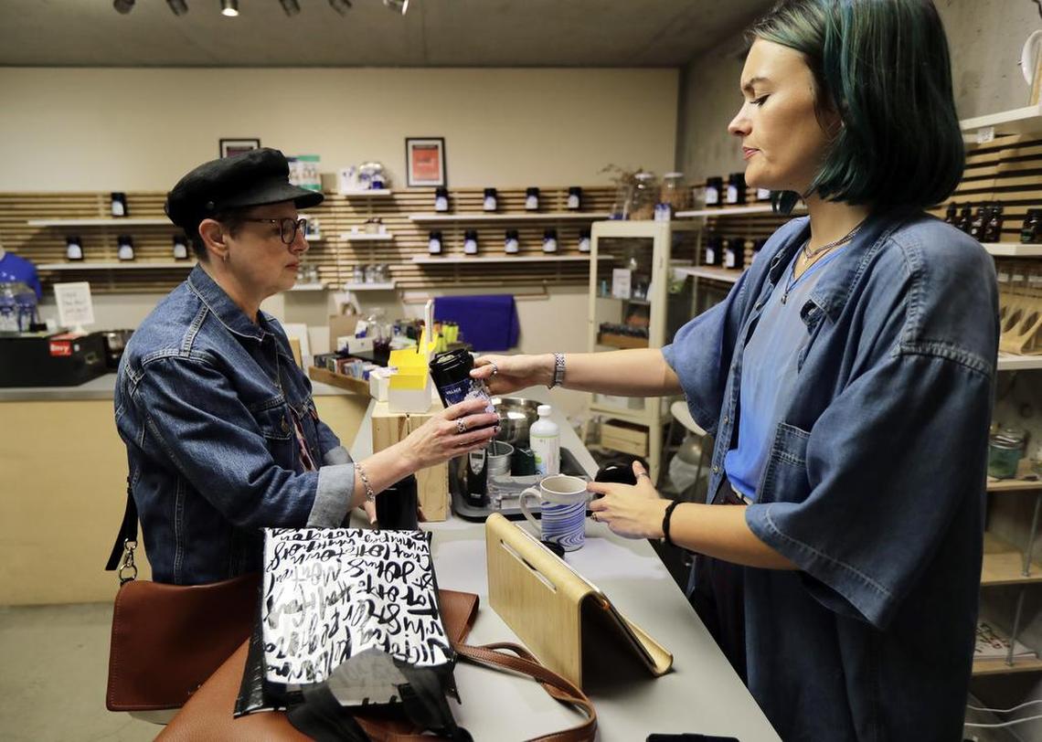 Wallis Muir, right, an employee at the Village Bloomery medical cannabis dispensary in Vancouver, British Columbia, helps customer Dolores Bzdel, left, make a purchase in September. On Oct. 17, Canada will become the second and largest country with a legal national marijuana marketplace, forcing many dispensaries, including the Village Bloomery, to stop selling many products, including vape pens, that they currently carry.