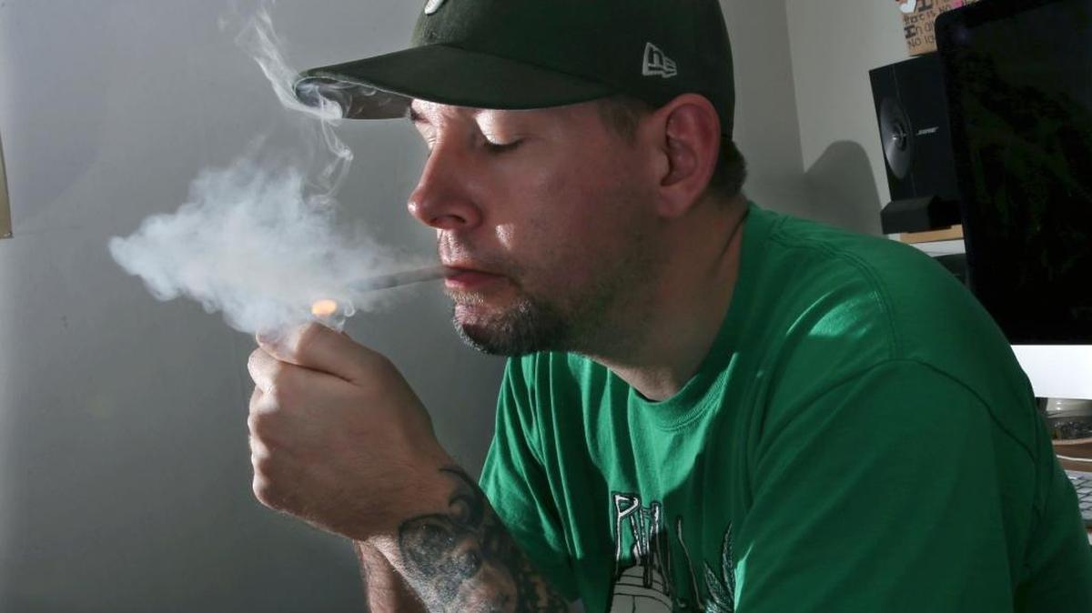 U.S. Marine veteran Mike Whiter lights a marijuana cigarette in March, 2016, before he starts editing a video project at his home in Philadelphia. A growing number of states are weighing whether to legalize marijuana to treat PTSD. While the research has been contradictory and limited, some former members of the military say marijuana helps them manage their anxiety, insomnia and nightmares.
