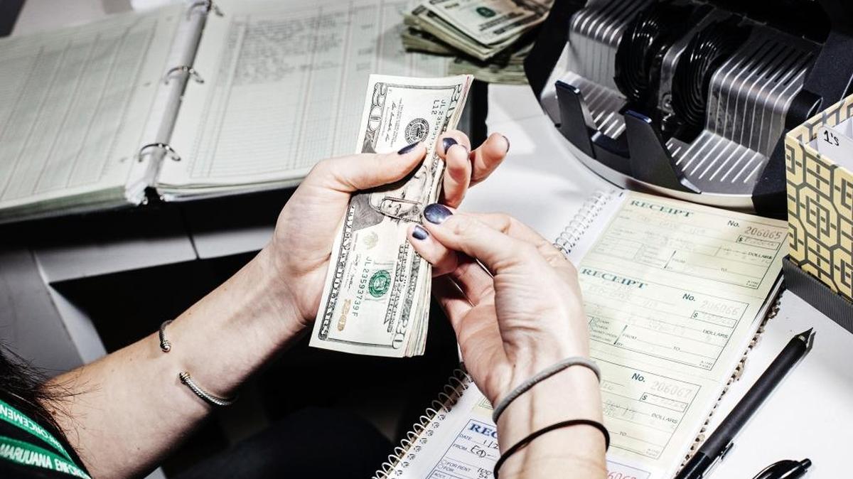 Paige Smith counts out money for payroll at Good Meds Dispensary in Lakewood Colo., Jan. 21, 2015. Legal marijuana businesses in Washington state still struggle to find financing as banks will not deal with them as long as pot remains illegal on the federal level.