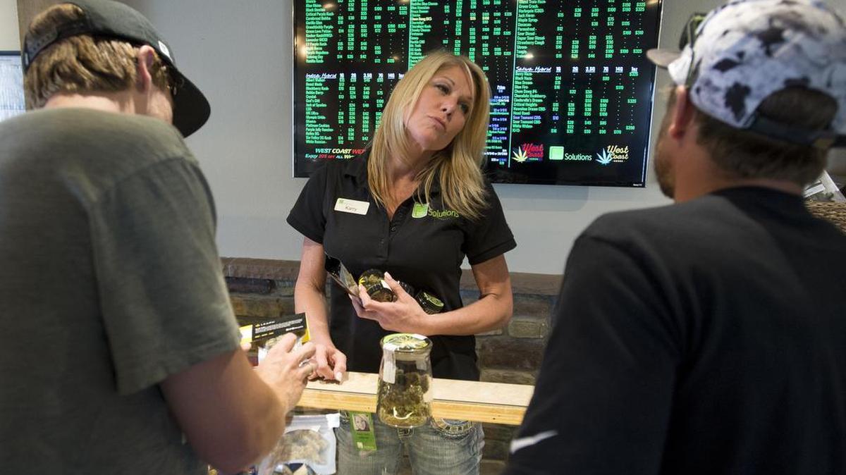 Karry Johnson, manager of 2020 Solutions on Iron Street, shows customers a variety of marijuana flowers on Wednesday, July 6, in Bellingham.