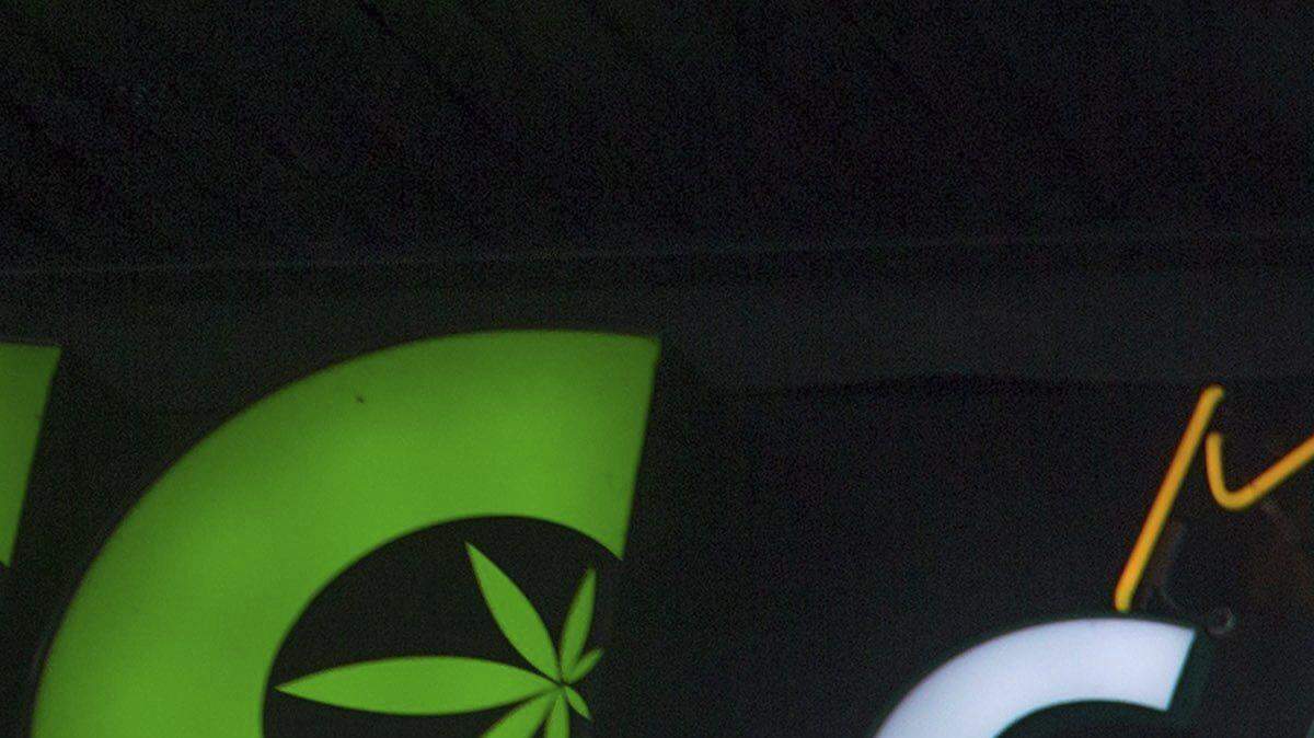 A woman smokes a joint as police officers stand outside the Cannabis Culture shop during a police raid, in Vancouver, British Columbia, on Thursday, March 9, 2017. Prominent marijuana activists Marc and Jodie Emery have been arrested in Toronto and police are raiding several pot dispensaries associated with the couple.