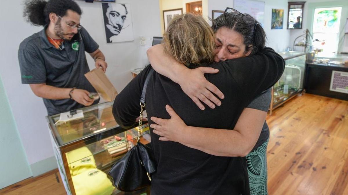 Owner Hugh Newmark, left, fills an order while patient Mary Burrell hugs employee Suzy Armus on the last day of business for Best Buds medical marijuana dispensary on Meridian Street in Bellingham, Wash., Thursday, June 30, 2016. “It sucks,” Newmark said.