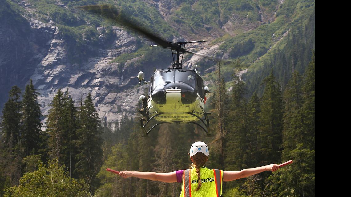 Katherine Jordan, with Snohomish County Search & Rescue, directs a helicopter onto a landing zone in the picnic area of the Big Four Ice Caves, in Washington to deliver equipment Tuesday, July 7, 2015.