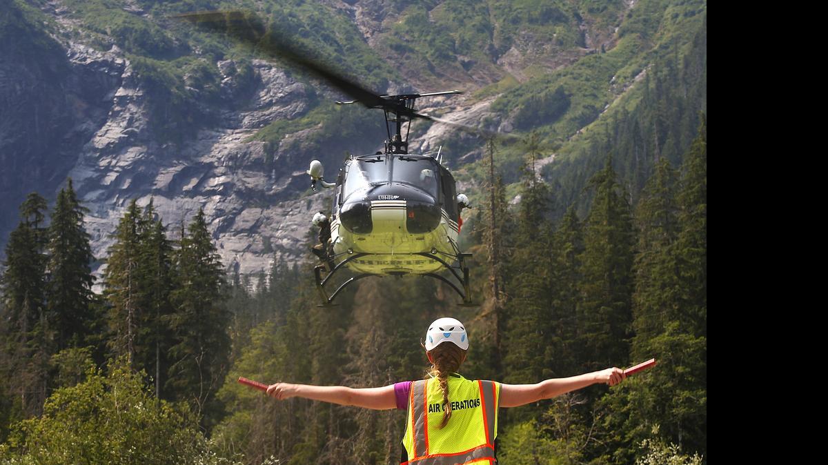 Katherine Jordan, with Snohomish County Search & Rescue, directs a helicopter onto a landing zone in the picnic area of the Big Four Ice Caves, in Washington to deliver equipment Tuesday, July 7, 2015.